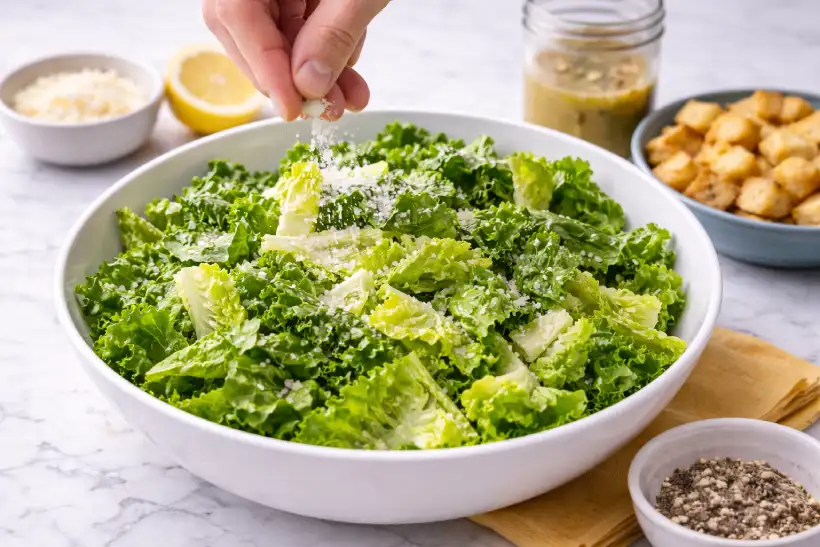 Salt being added directly to romaine lettuce in a mixing bowl