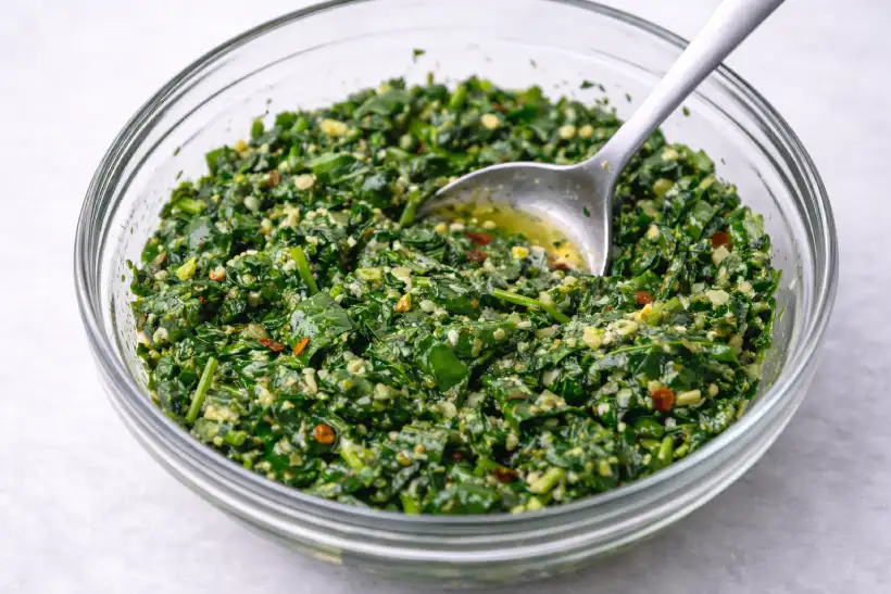 Finely chopped spinach mixed with olive oil to reduce moisture before baking on puff pastry pizza