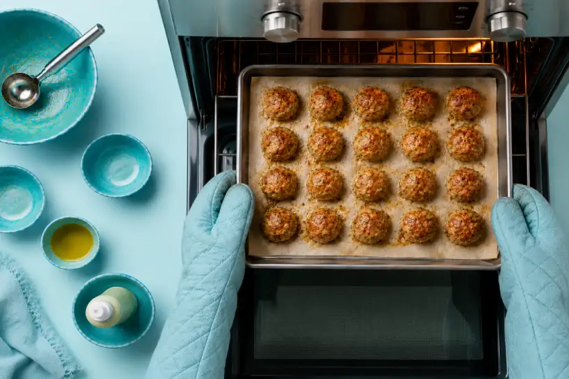 Raw bariatric chicken meatballs on a parchment-lined baking sheet