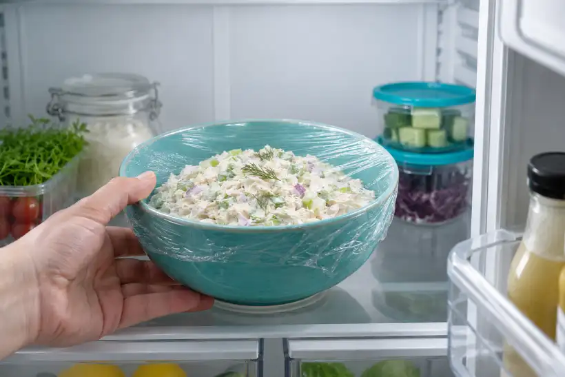 Covered bowl of bariatric chicken salad being placed in the refrigerator