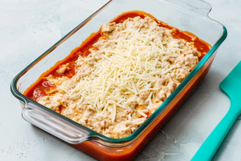 Unbaked bariatric chicken enchilada casserole topped with shredded cheese